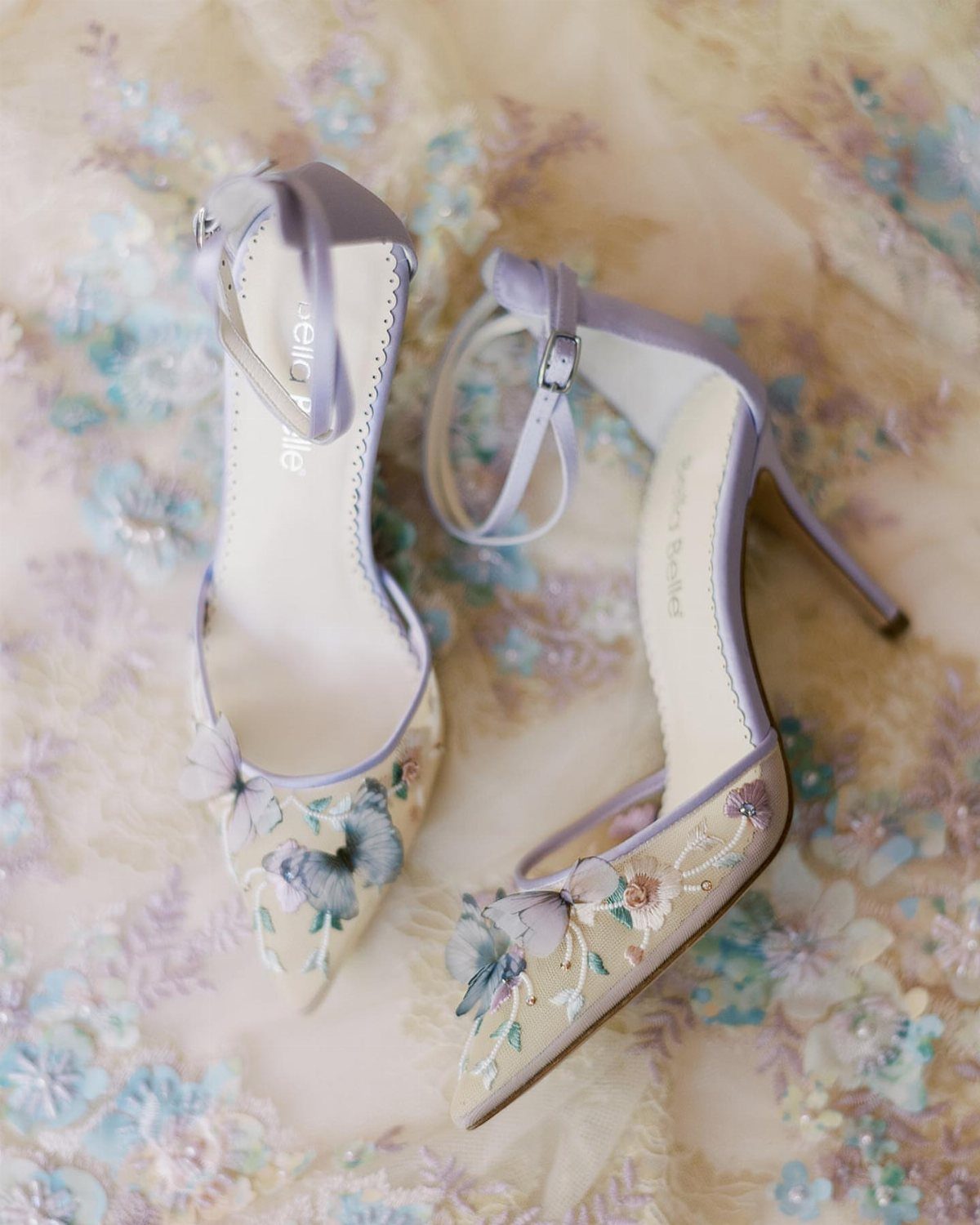 Pointed-toe bridal heels with purple straps and blue floral embroidery on sheer fabric