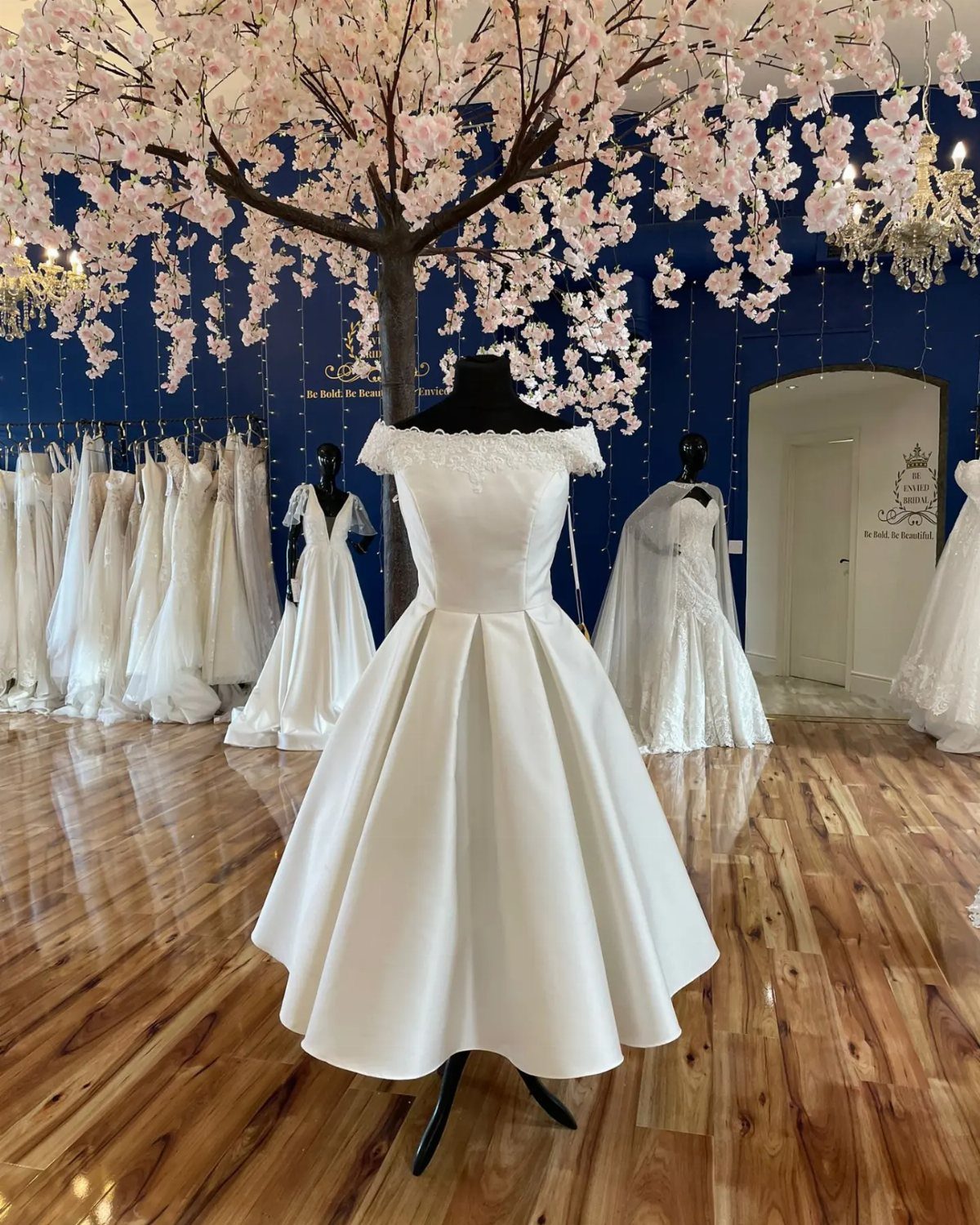 White tea-length wedding dress on a mannequin in a bridal boutique setting