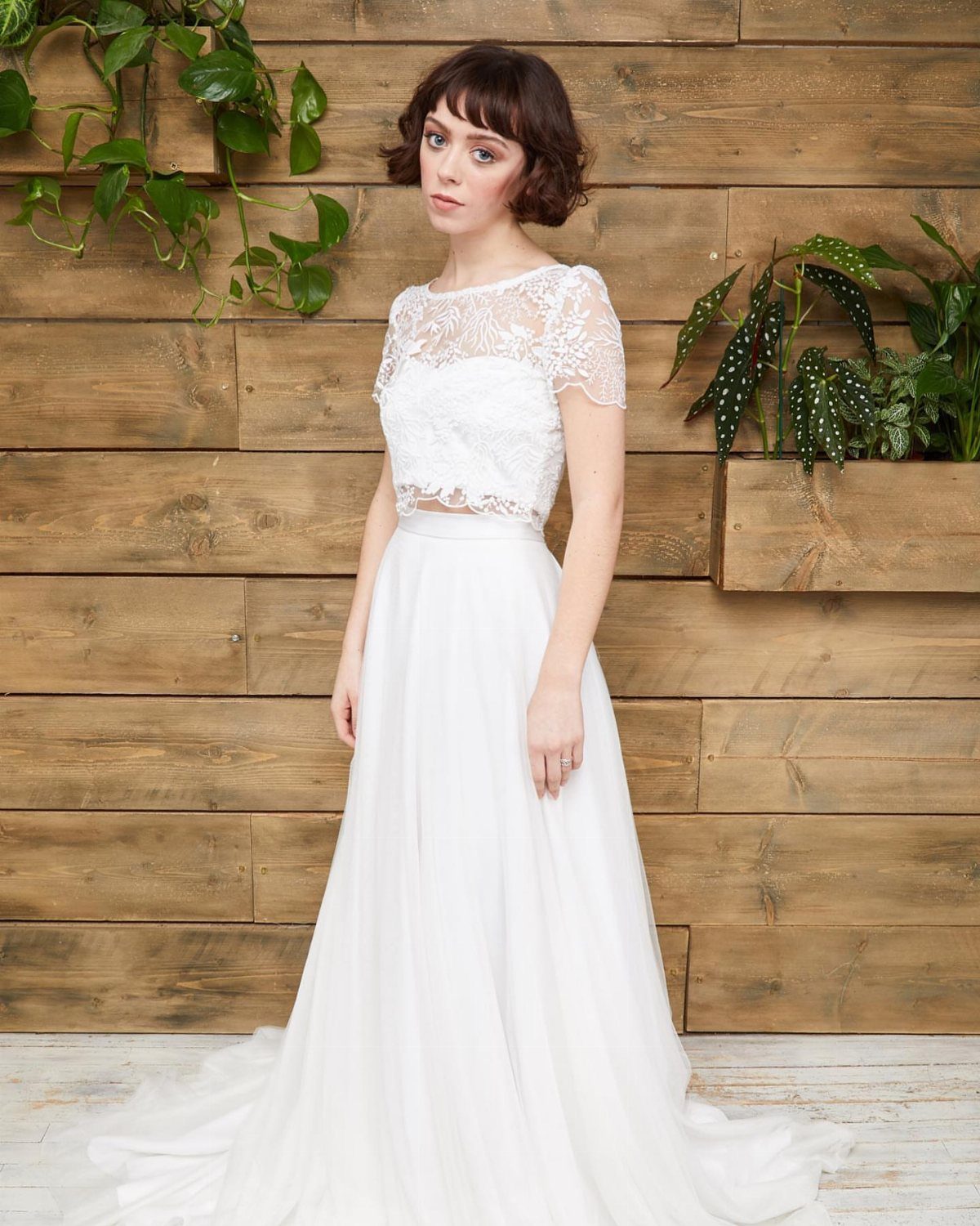 Woman wearing a white lace bridal crop top and a long flowing skirt.