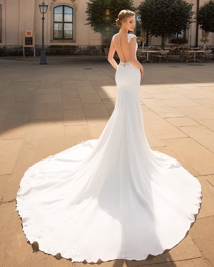 Woman in a white trumpet wedding dress with a long train on a plaza