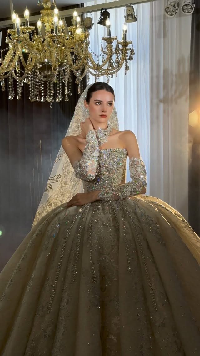 Woman in a sparkling champagne ballgown with detached sleeves and a lace veil.
