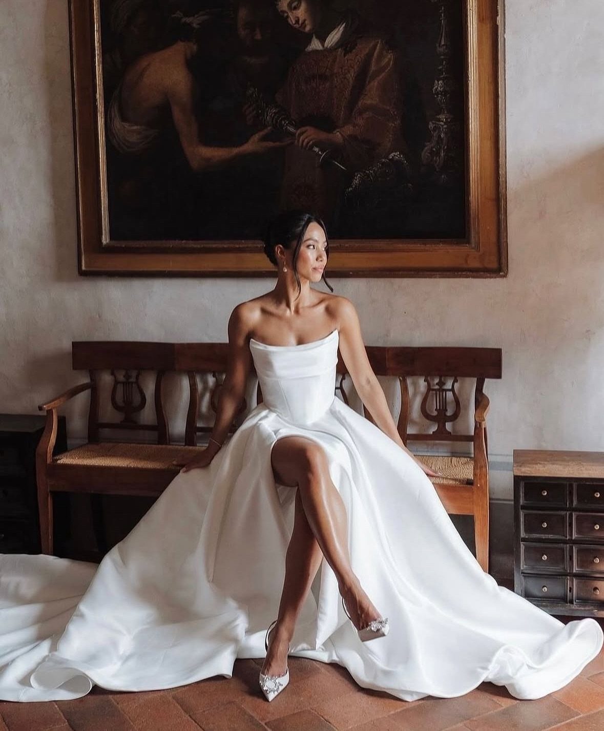 Woman in a strapless white satin wedding gown with a voluminous statement skirt.