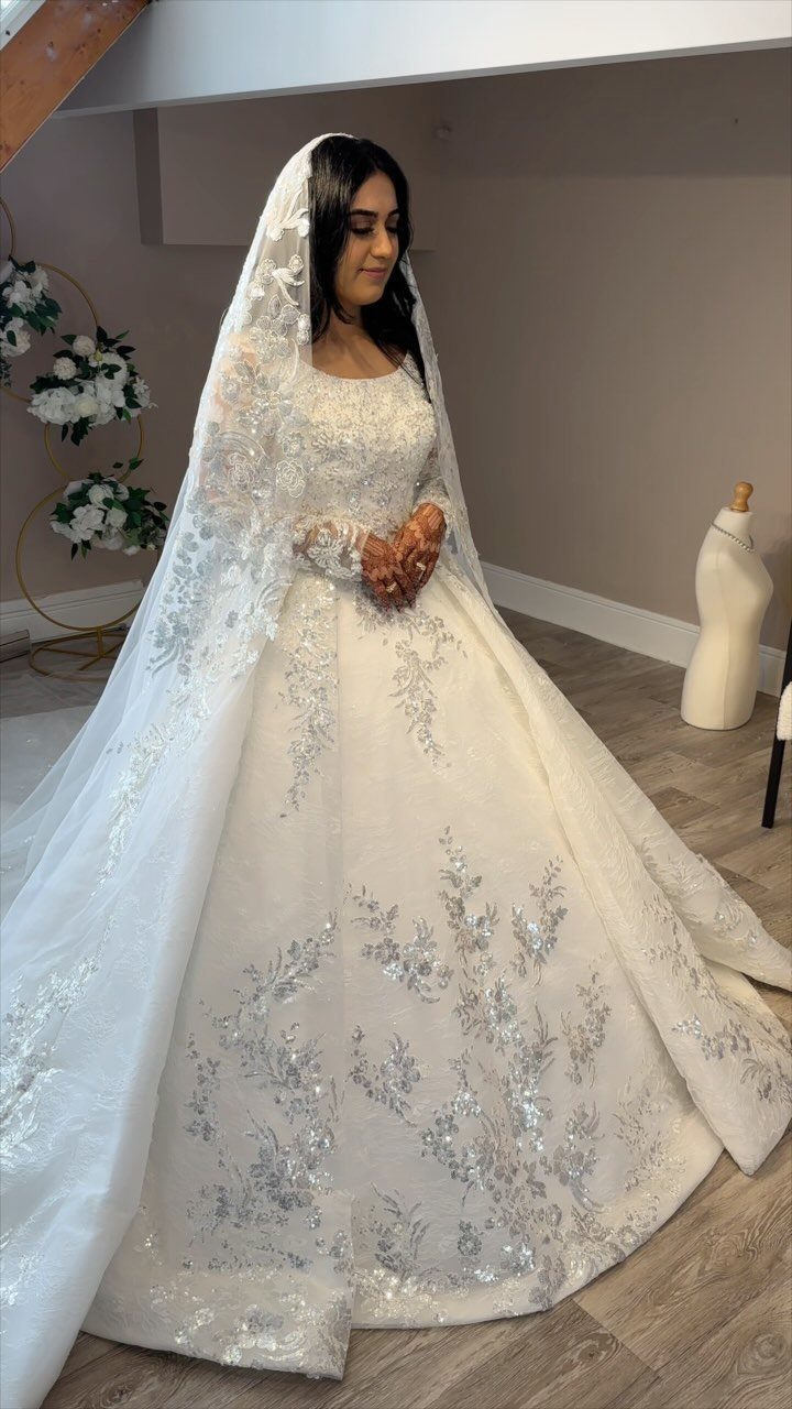 Woman in a white Arabic wedding dress with silver beadwork and a veil.