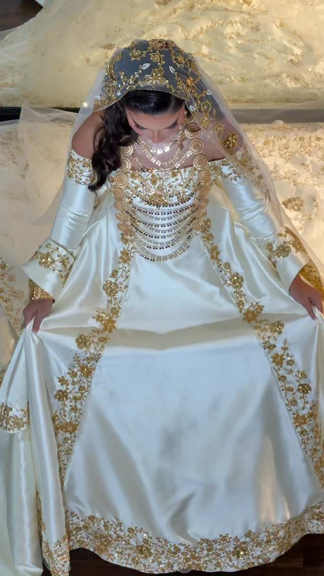 Woman in a white and gold embroidered Arab wedding dress with a veil.