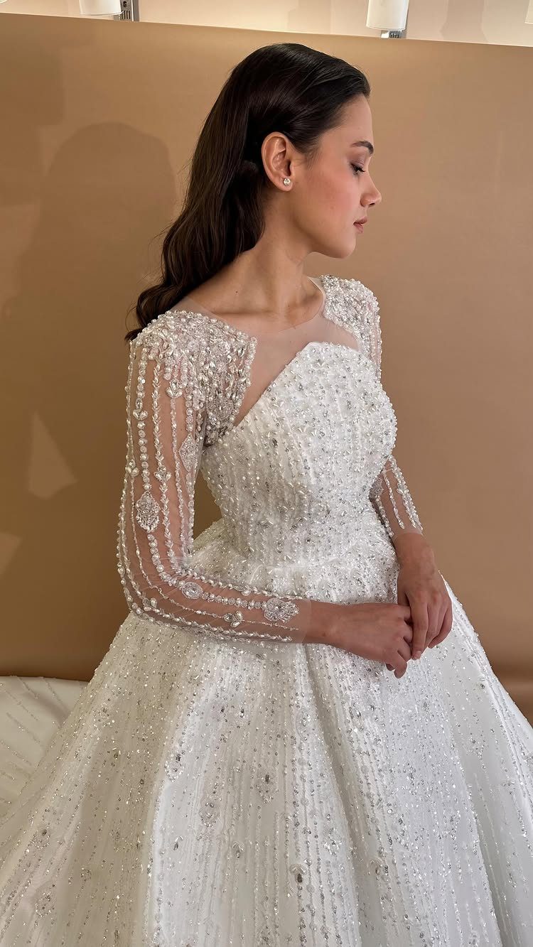 Woman in a white wedding gown with heavily beaded sleeves and bodice.