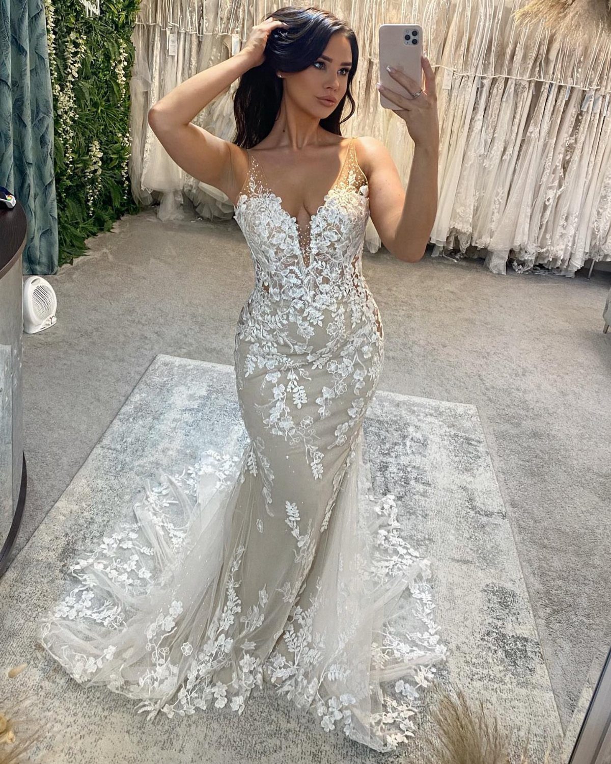 Woman in a beaded white lace mermaid wedding dress taking a mirror selfie.