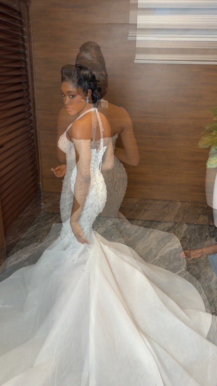 Woman in a white beaded wedding gown with sheer sleeves and a full skirt.