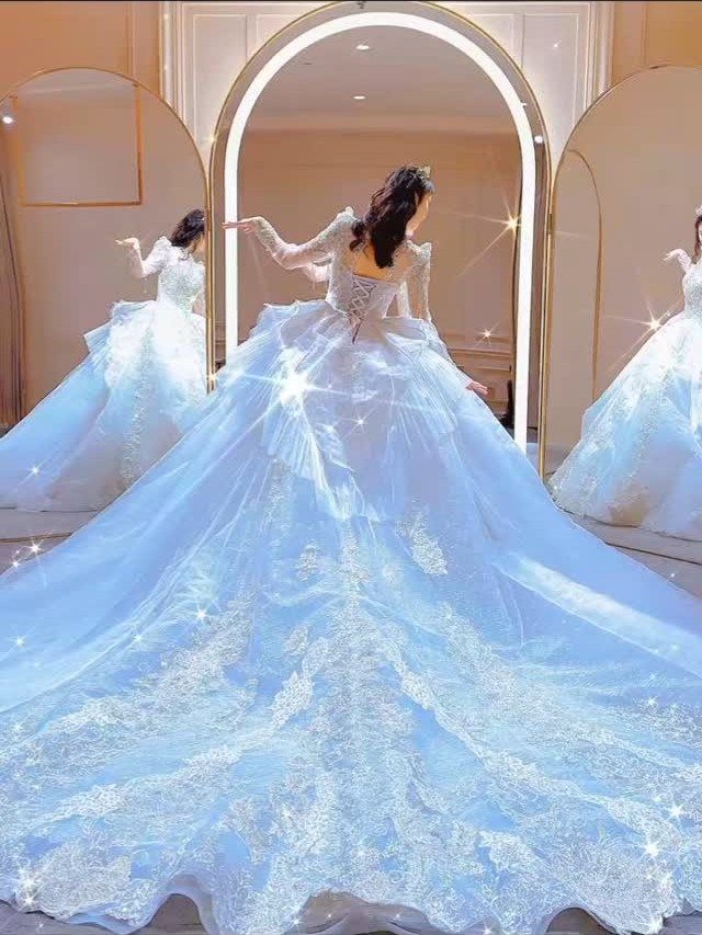 Woman in a sparkling light blue Cinderella ballgown wedding dress with a long train.