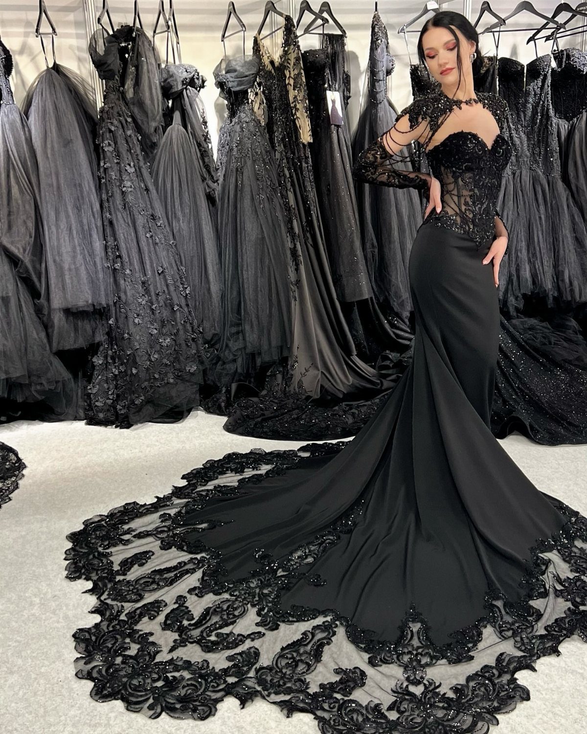 Woman in a black form-fitting gown with a floral lace embroidered train.