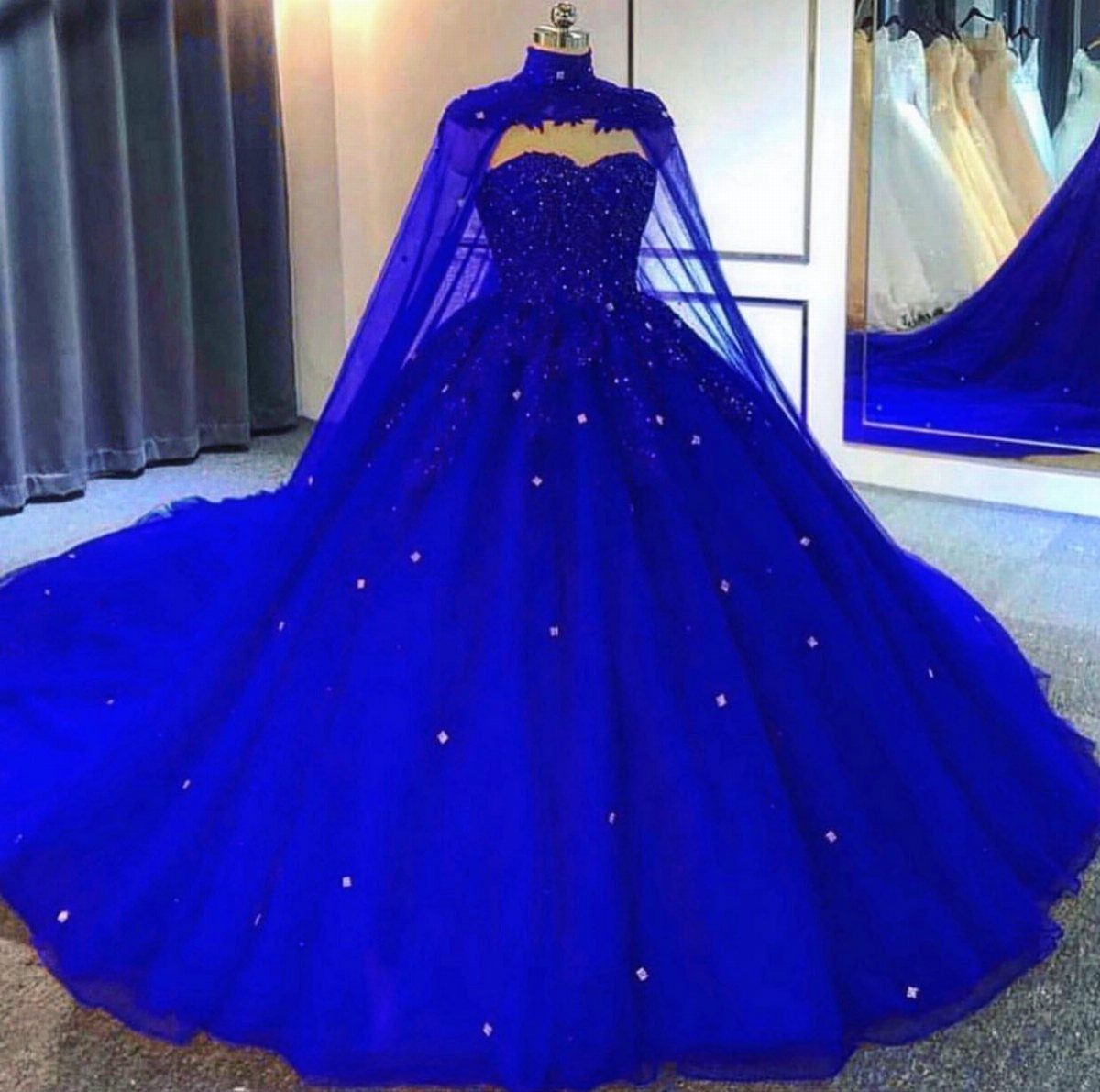 Royal blue ballgown wedding dress with a matching sheer cape on a mannequin