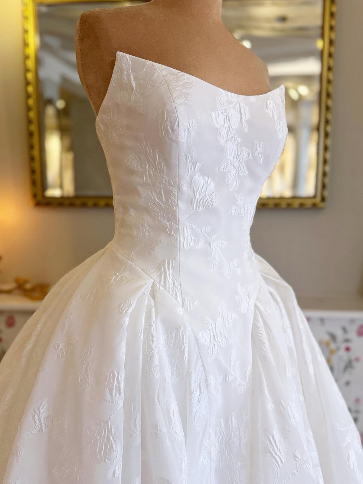 White strapless wedding dress with woven floral jacquard patterns on a mannequin.