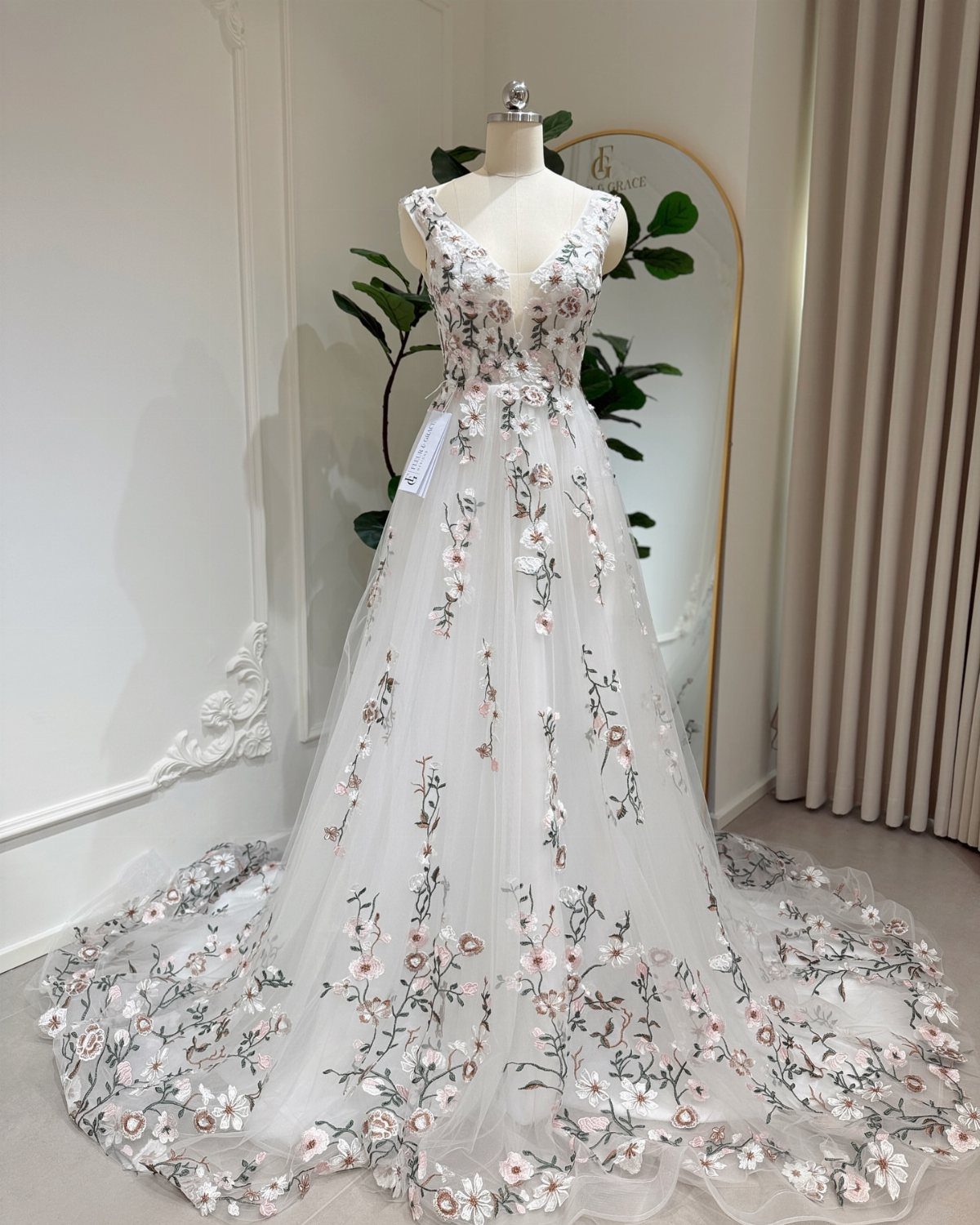 White wedding gown on mannequin with pink and green floral embroidery and 3D flowers.