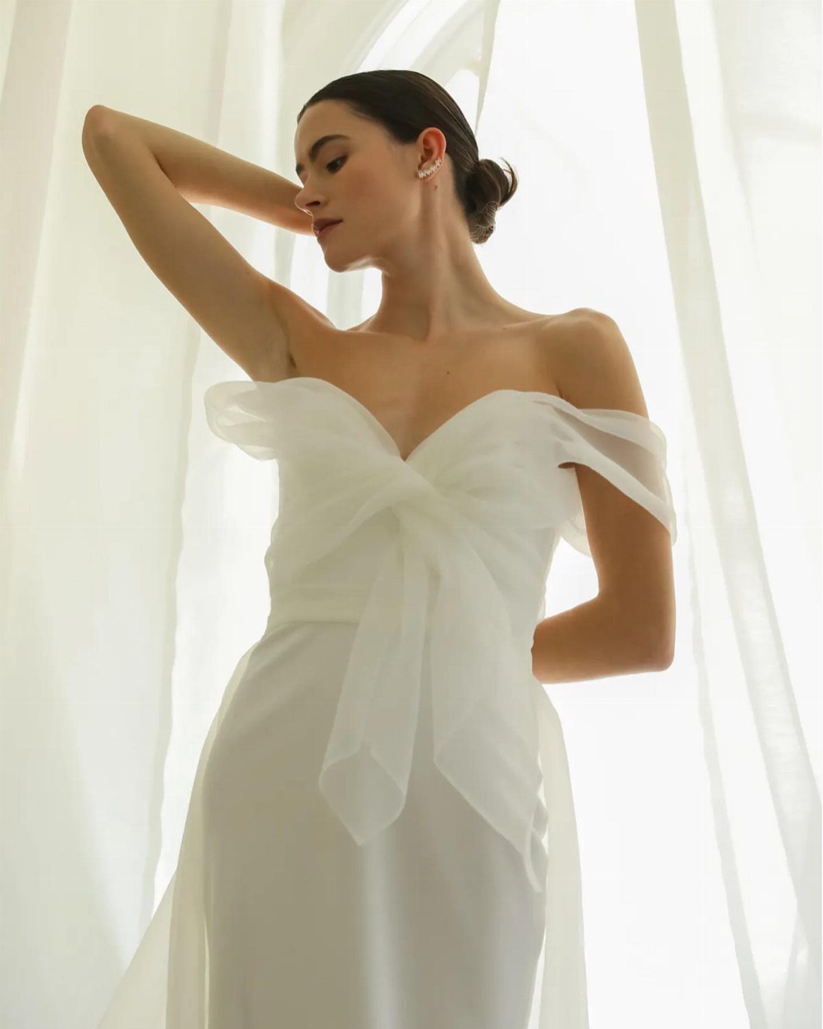 Woman in a white wedding dress with a sheer organza bow on the bodice.