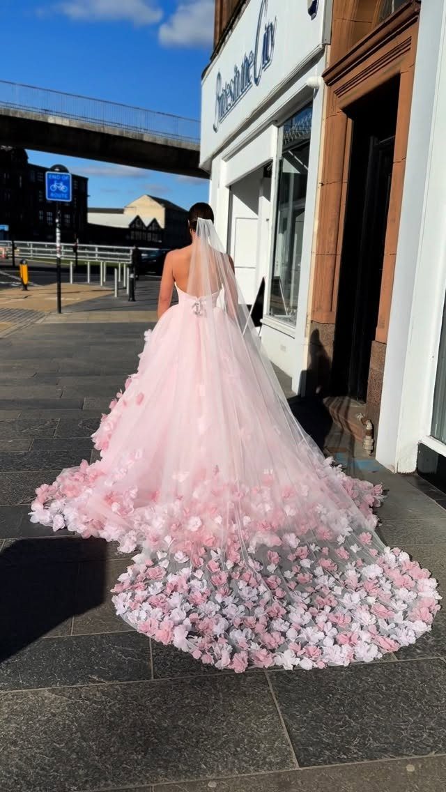 Woman from behind in a pink wedding dress with a floral train and veil.