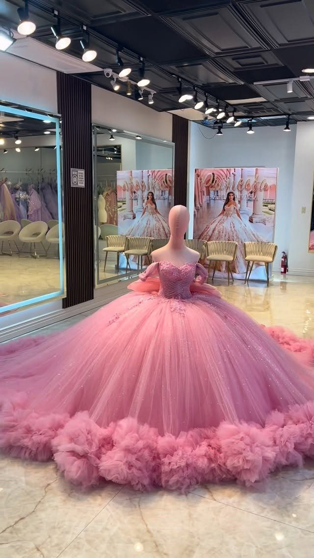 Pink tulle wedding dress with a voluminous ruffled skirt on a mannequin.