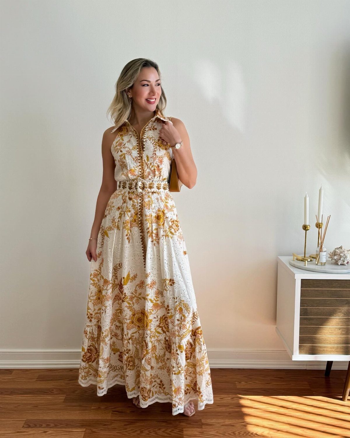 Woman wearing a white floral maxi dress with a matching belt and handbag.