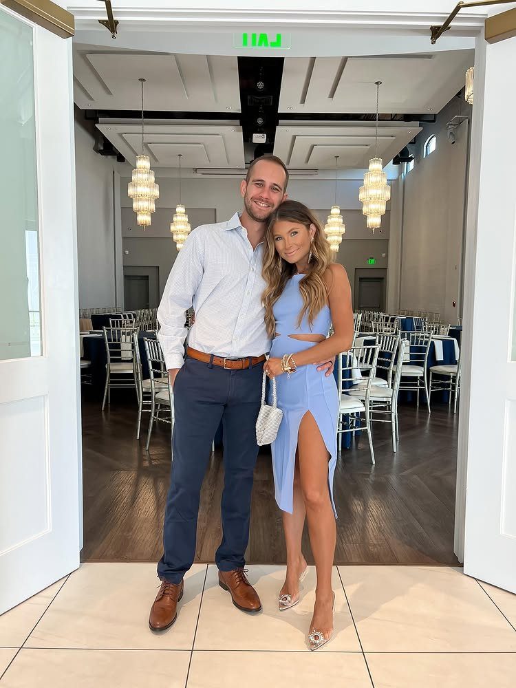 Couple posing in a doorway, woman wearing a light blue cocktail midi dress.