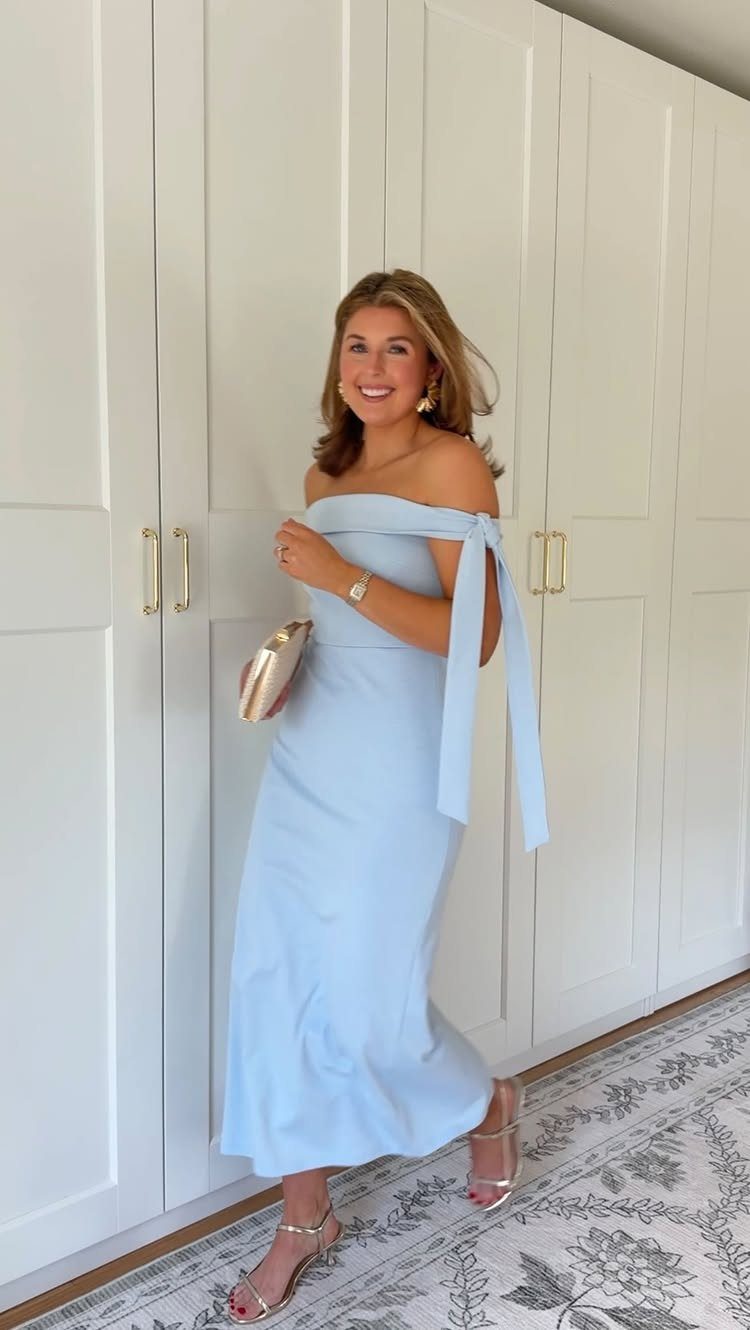 Woman wearing a light blue off-the-shoulder maxi dress with a gold clutch and silver heels.