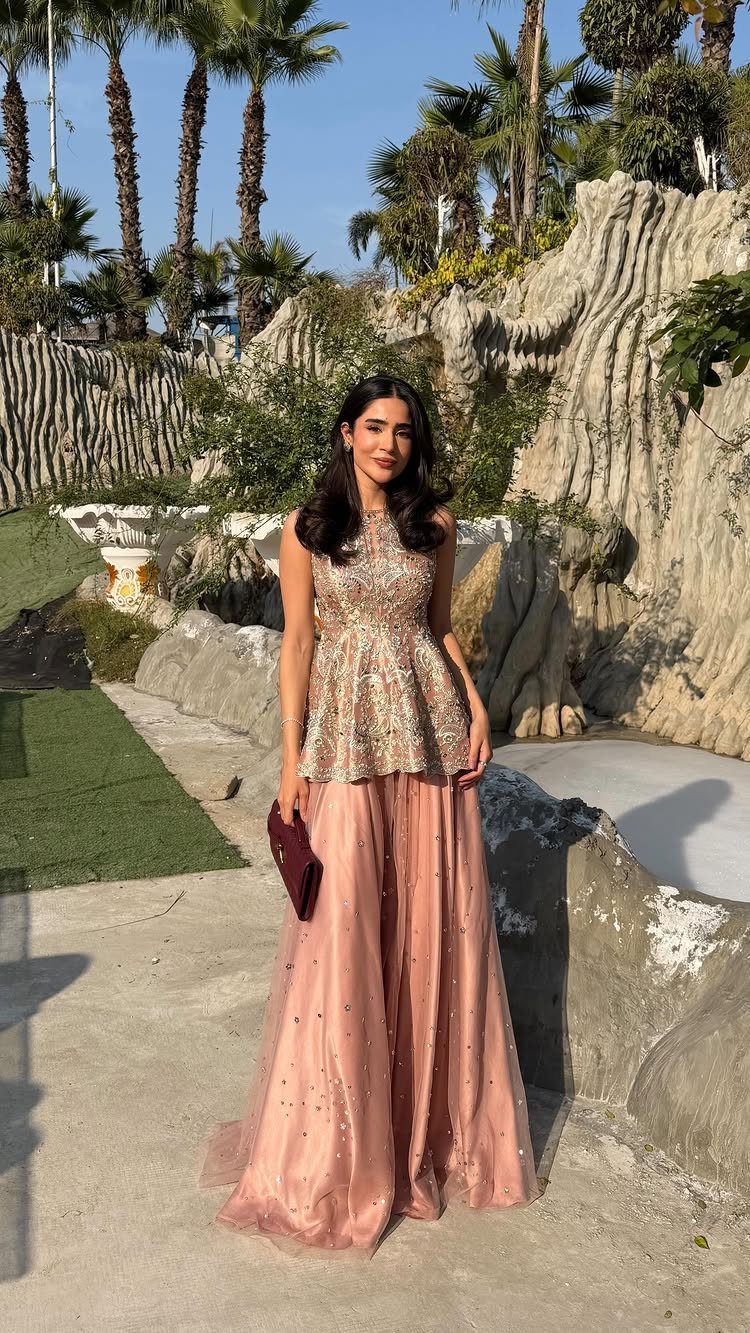Woman in gold sequined top and rose tulle skirt posing by rocky cliffs