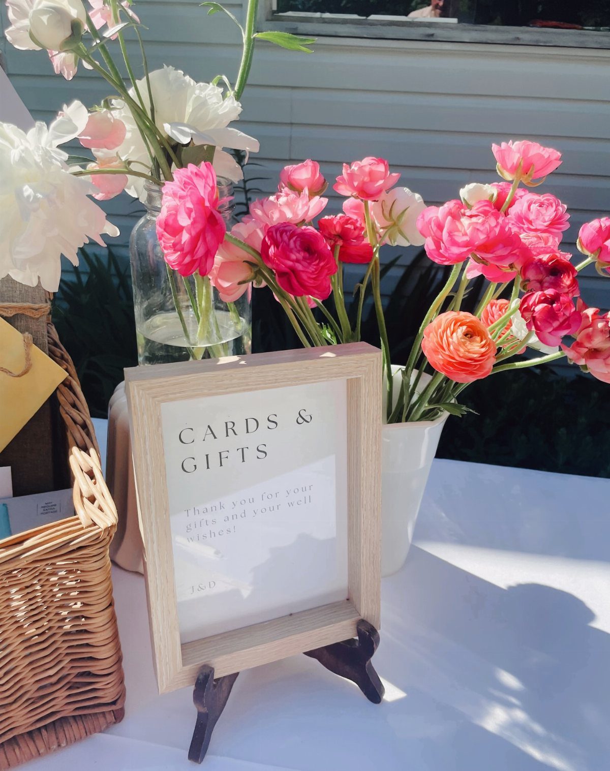 Gift table with a cards and gifts sign, wicker basket, and pink flowers.