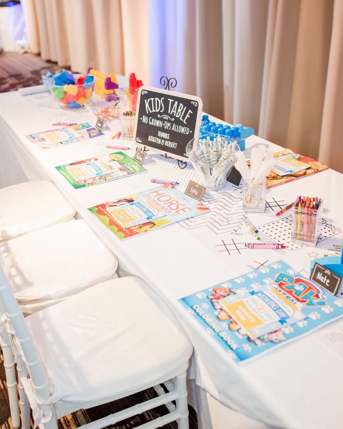 Kids activity table at a wedding with coloring books, crayons, and a sign.