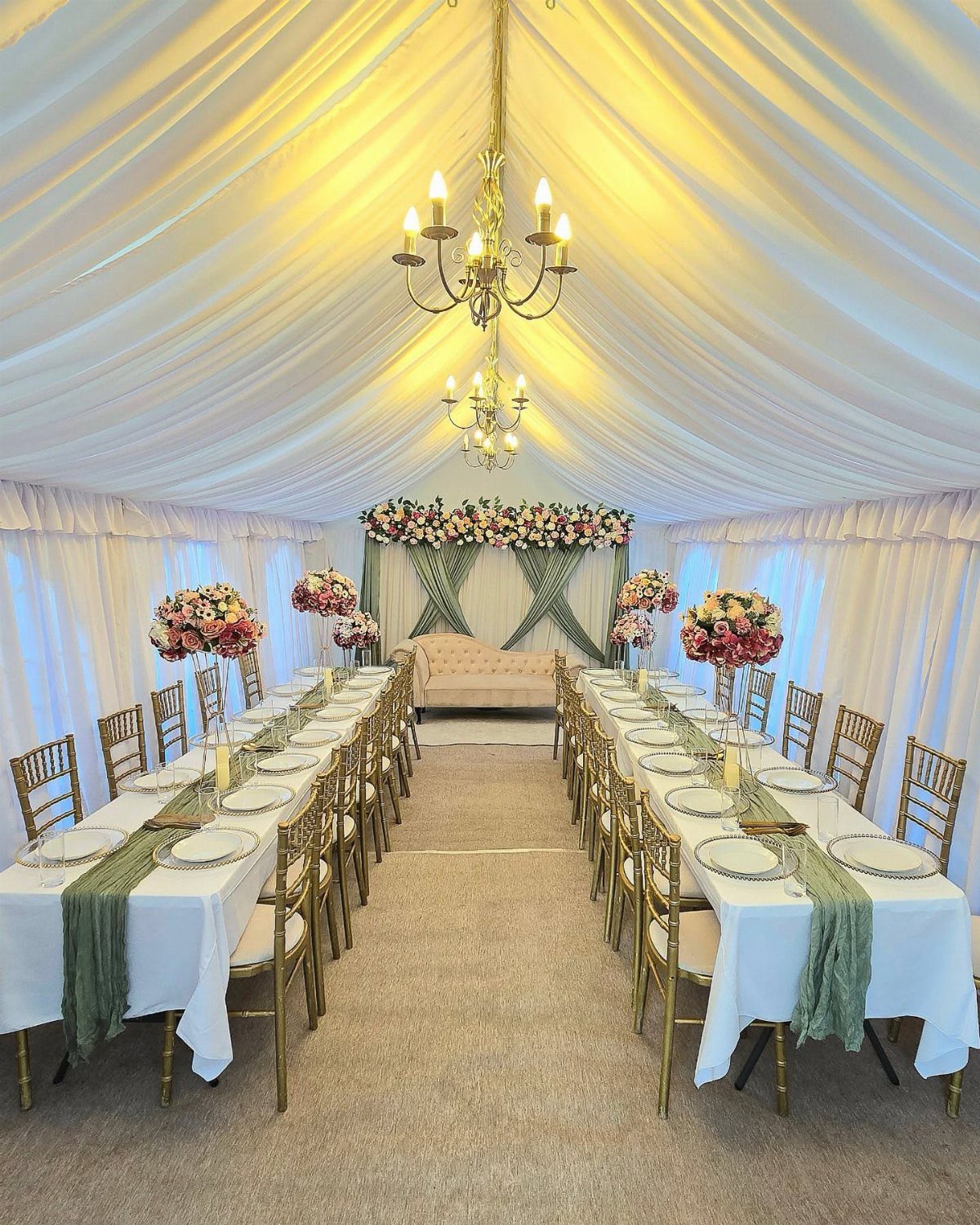 Two long rectangular wedding guest tables with white linens and gold chairs.