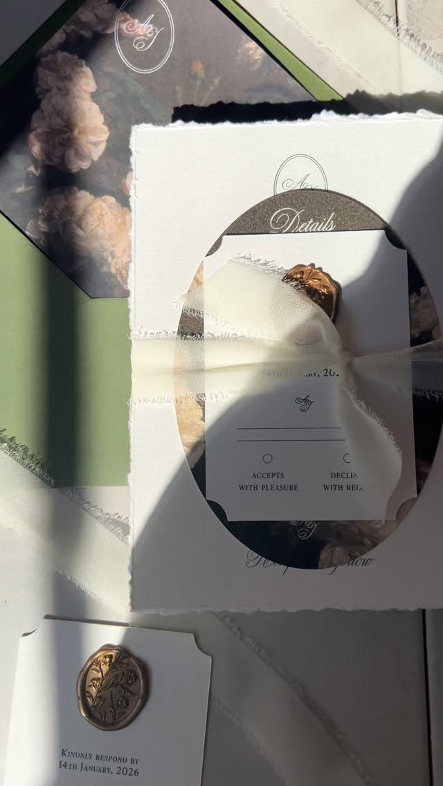 Wedding invitation suite with deckle-edged paper, white ribbon, and gold wax seal.