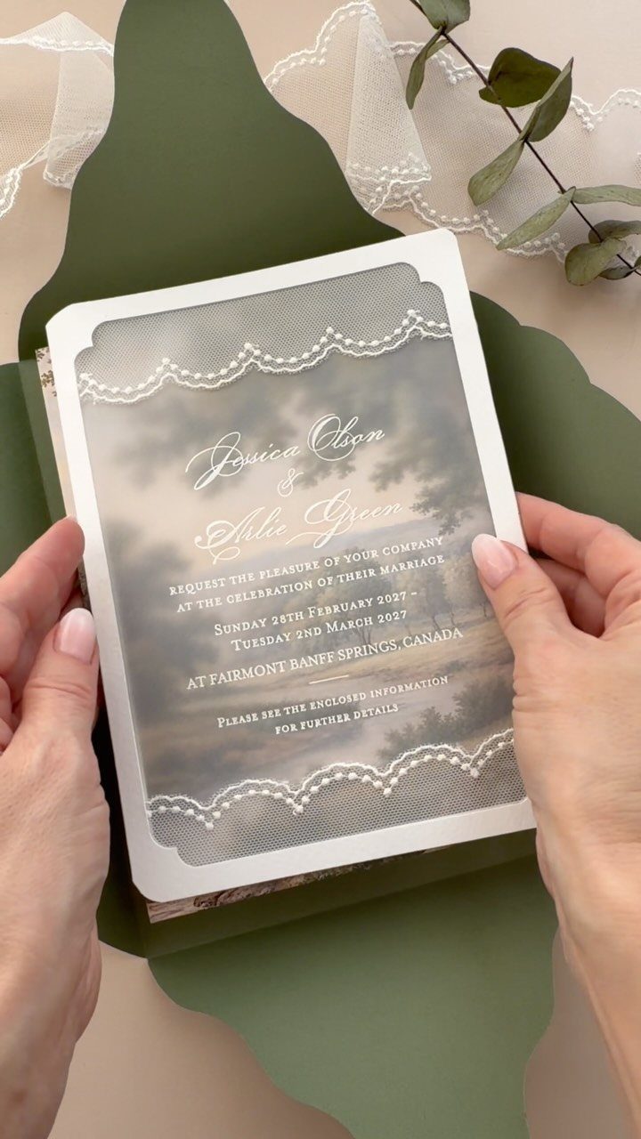 Wedding invitation with elegant script held by hands over a green scalloped background.