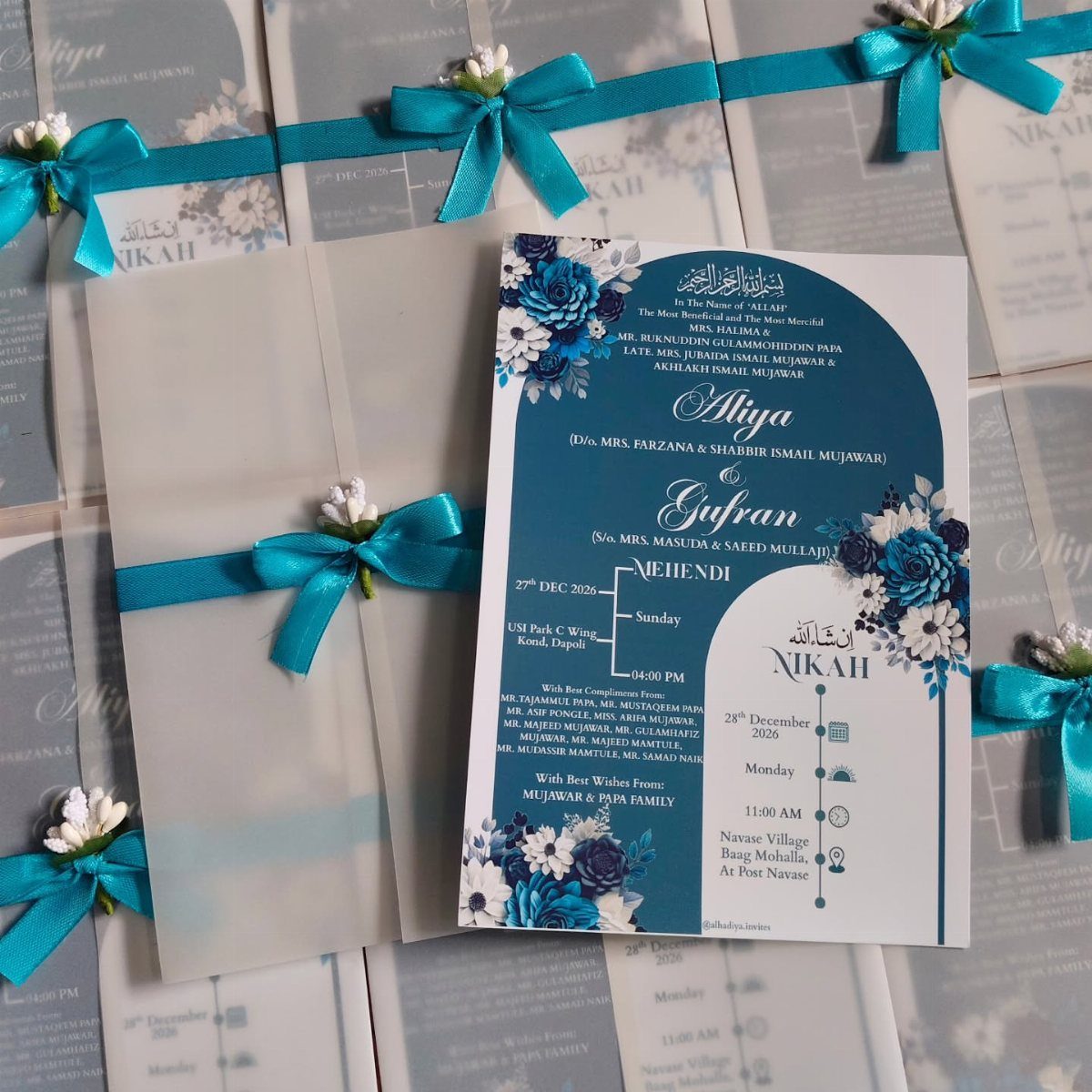 Wedding invitation suites with blue floral designs and vellum envelopes tied with blue ribbons.