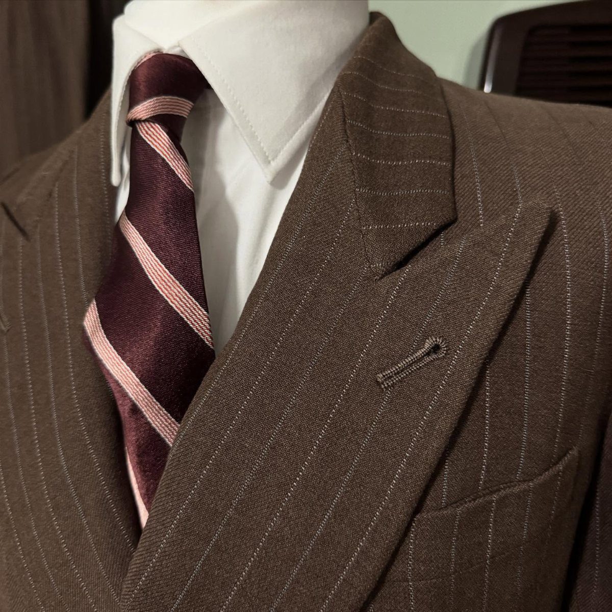 Brown pinstripe suit jacket with a white shirt and burgundy striped tie.