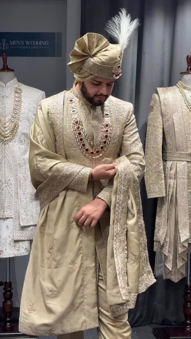 Man in gold embroidered sherwani and turban posing in a wedding couture shop