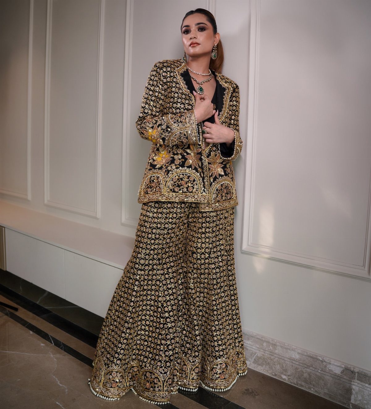 Woman wearing a black bridal blazer and wide-leg pants with gold embroidery.