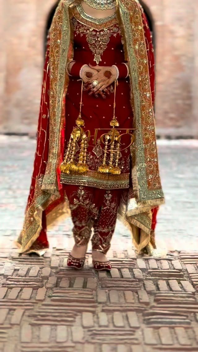 Bride in a red and gold traditional embroidered wedding suit on brick pavement