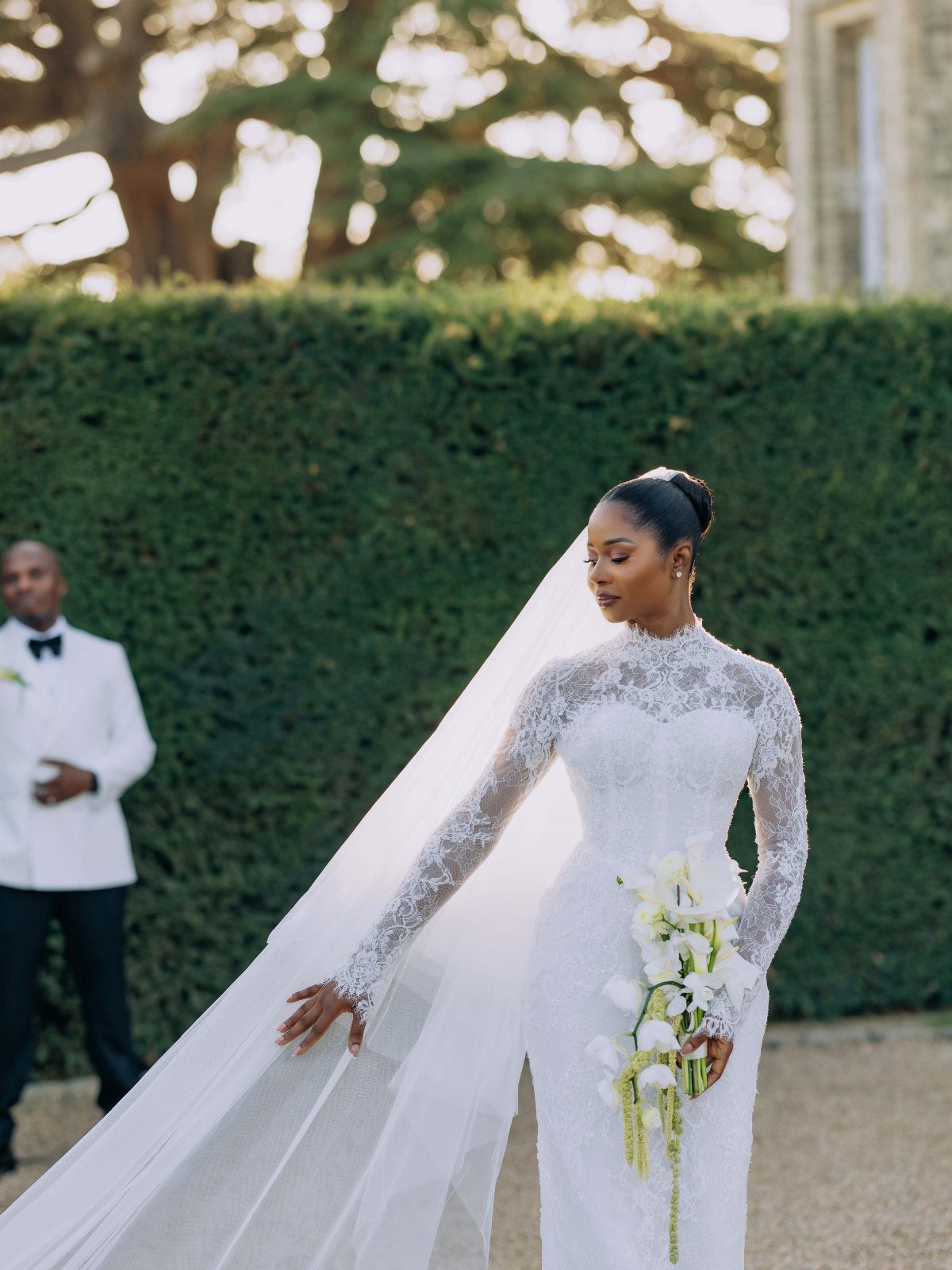 Bride in a white lace wedding dress with long sleeves and a veil.