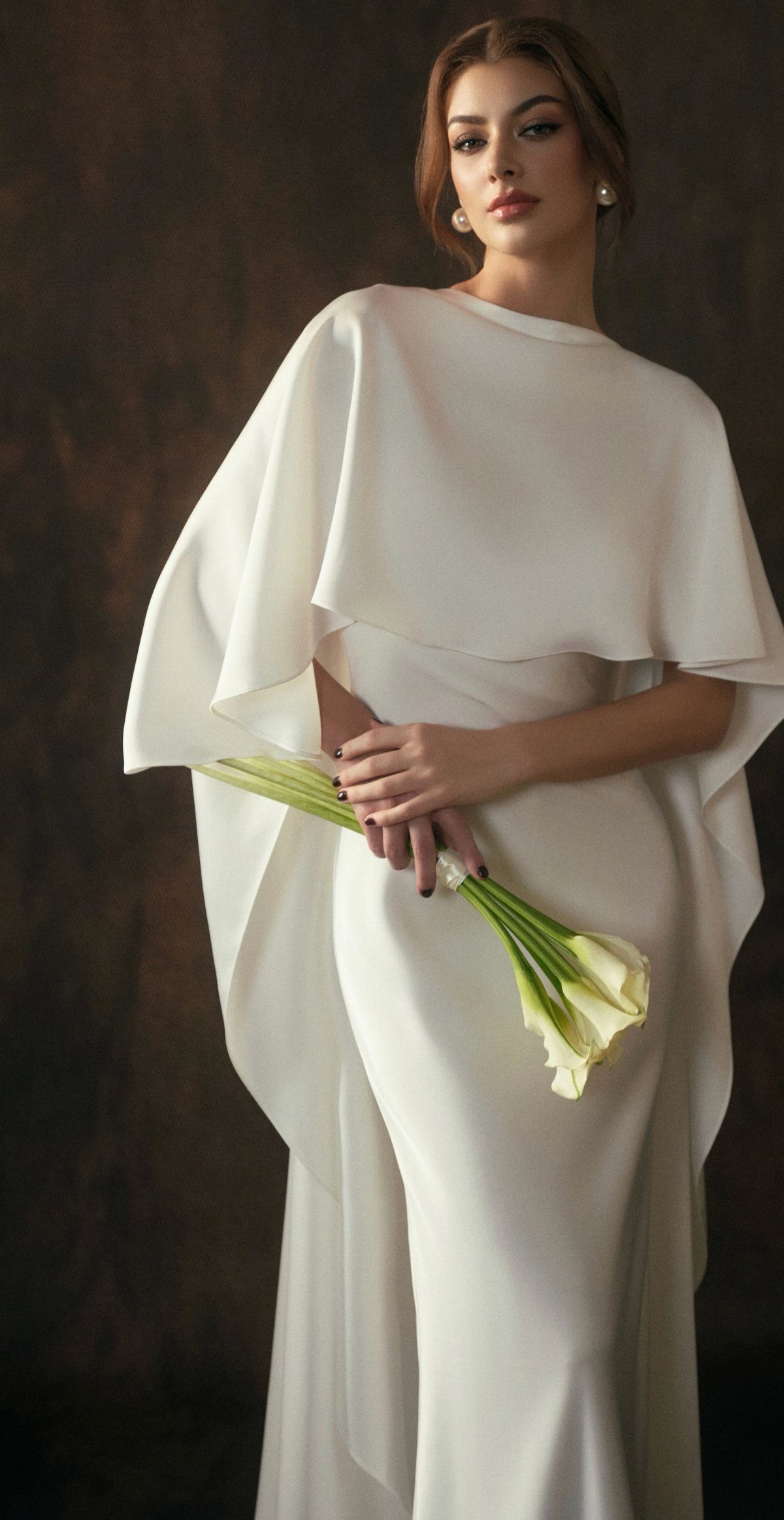 Woman in a minimalist white wedding dress holding white calla lilies