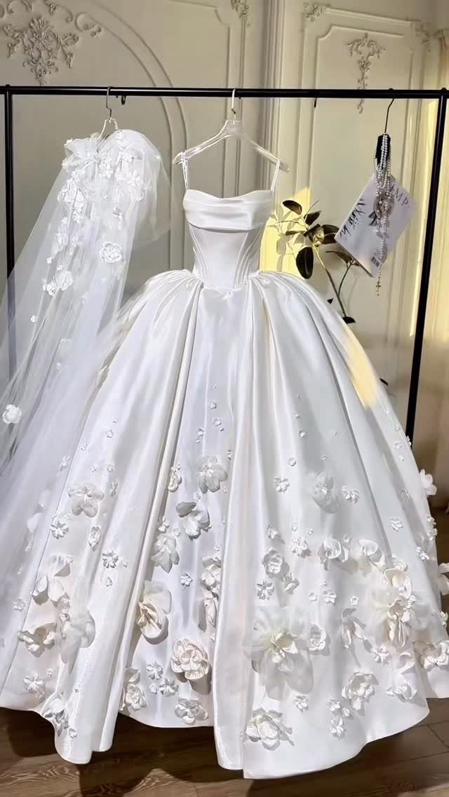 White strapless ball gown wedding dress with 3D floral details on a rack.